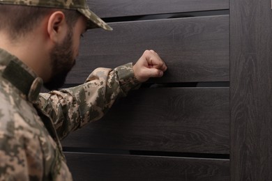 Photo of Military commissariat representative knocking on wooden door, selective focus