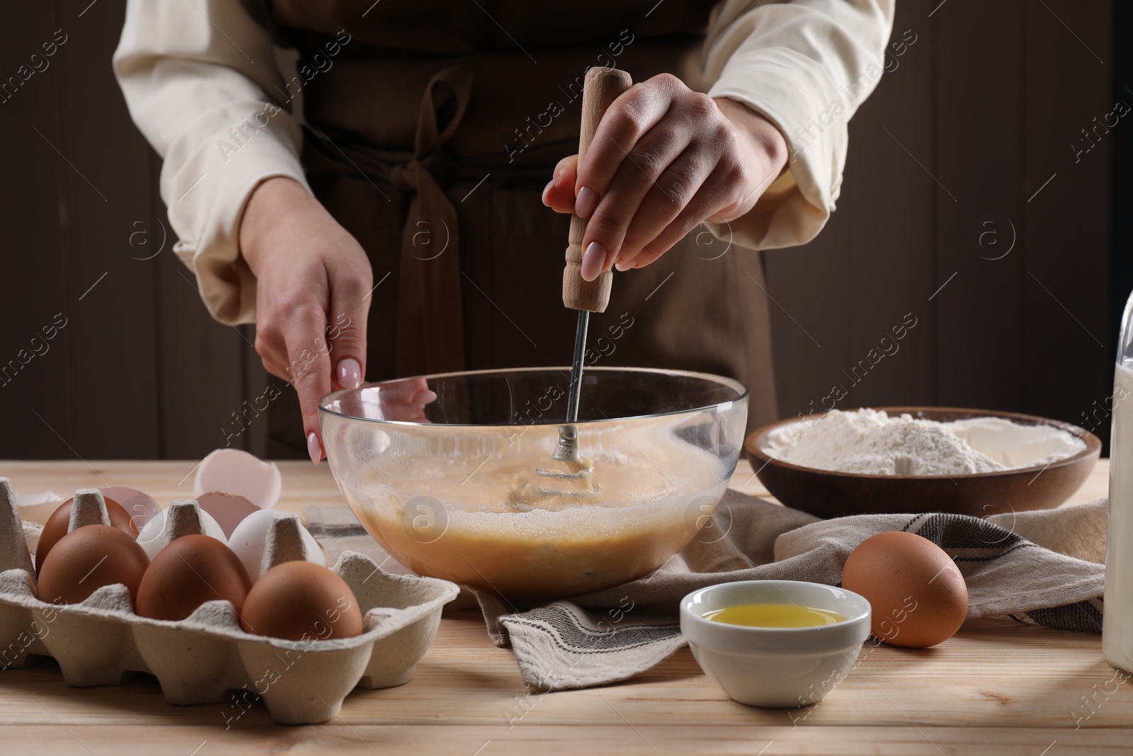 Photo of Woman making dough with whisk in bowl at table, closeup