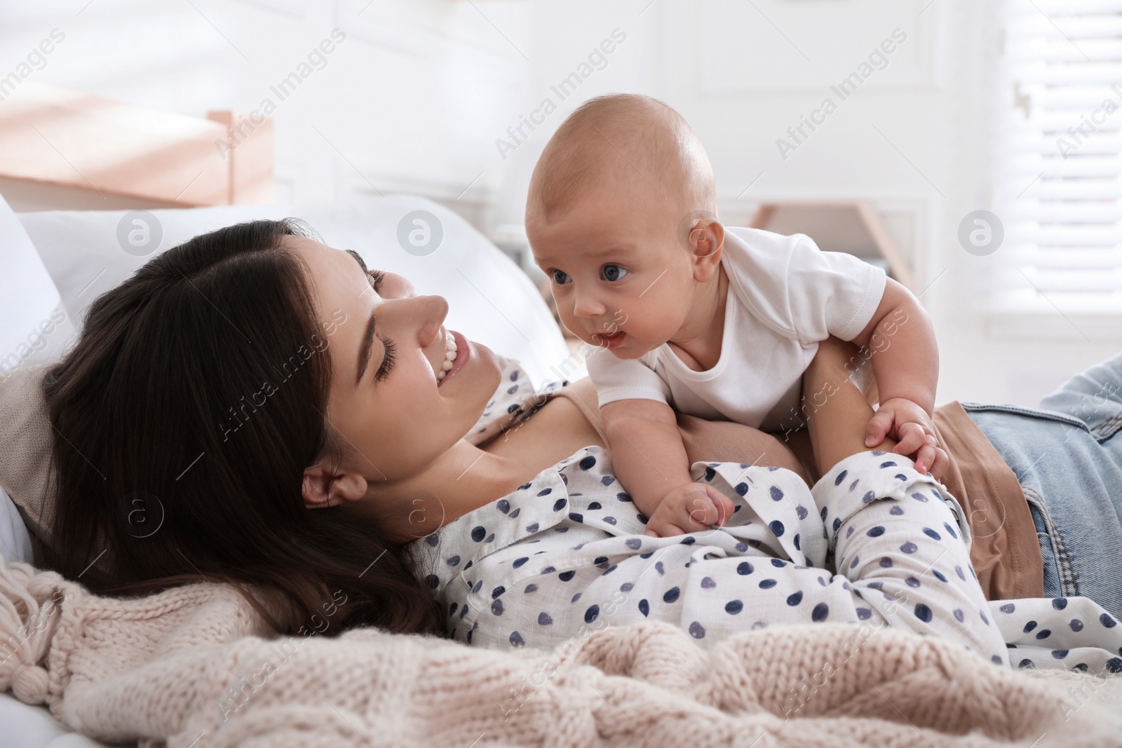 Photo of Mother with her cute baby on bed at home