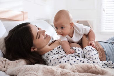 Photo of Mother with her cute baby on bed at home