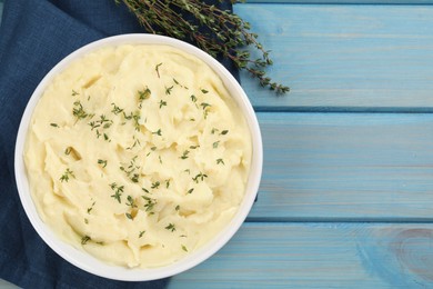 Bowl of tasty mashed potato with rosemary on light blue wooden table, flat lay. Space for text