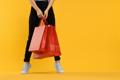 Photo of Woman with shopping bags on yellow background, closeup. Space for text