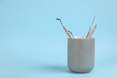Photo of Holder with set of dentist's tools on light blue background. Space for text