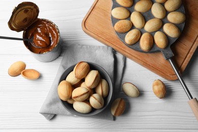Delicious walnut shaped cookies with condensed milk on white wooden table, flat lay