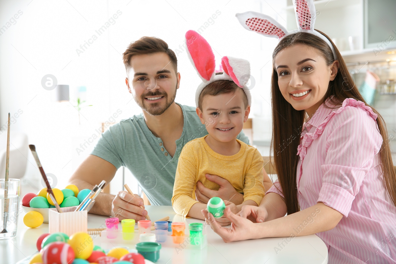 Photo of Happy family painting Easter eggs in kitchen. Festive tradition