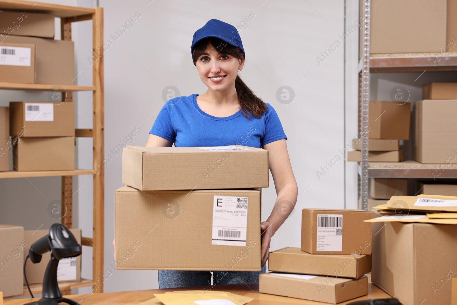 Photo of Parcel packing. Post office worker with parcels at wooden table indoors