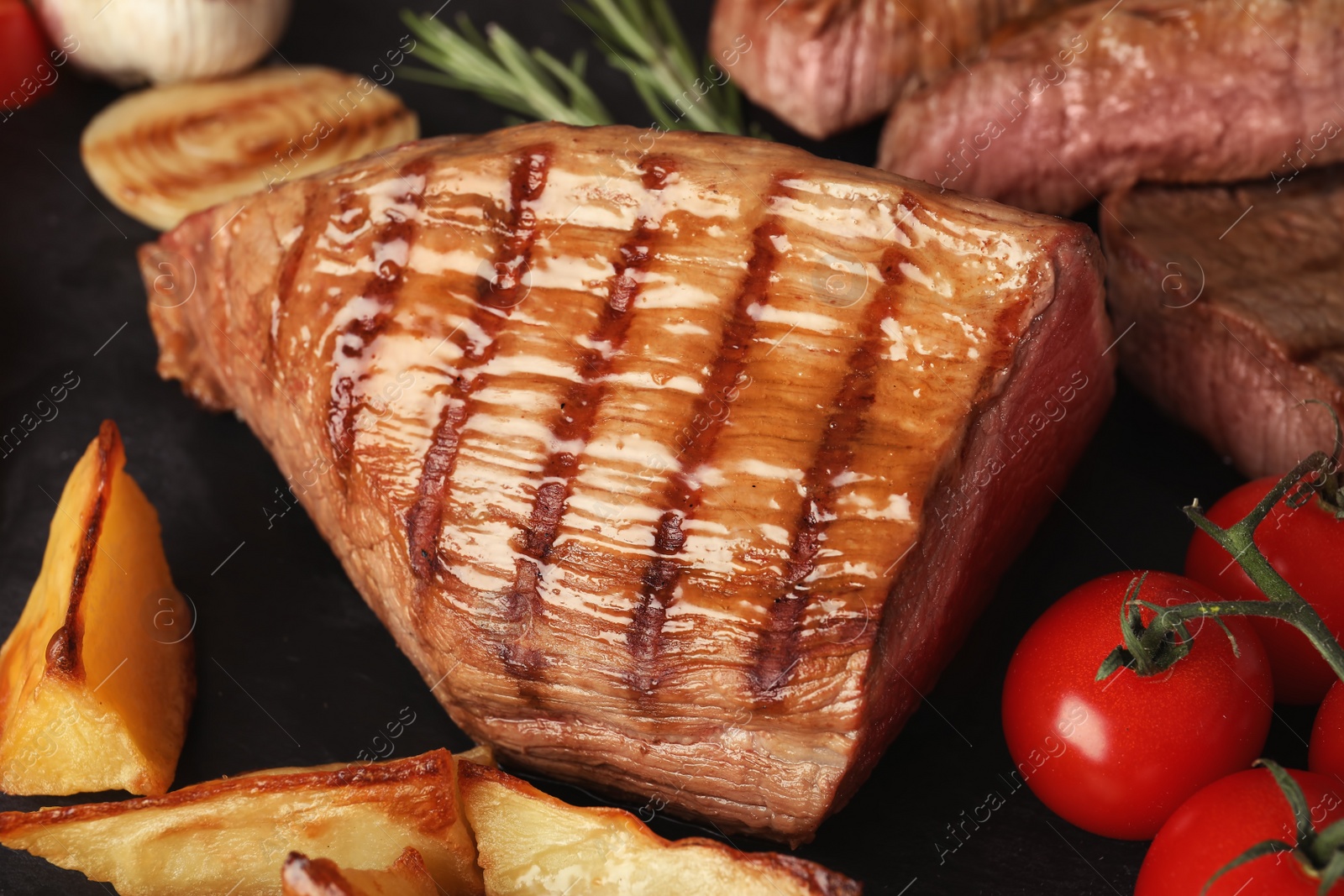 Photo of Grilled meat with garnish on slate plate, closeup