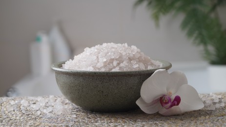 Photo of Bowl with bath salt and flower on wicker mat indoors, closeup