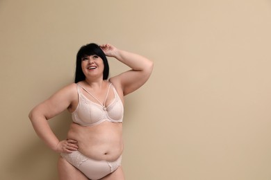Photo of Beautiful overweight woman in underwear on beige background, space for text. Plus-size model