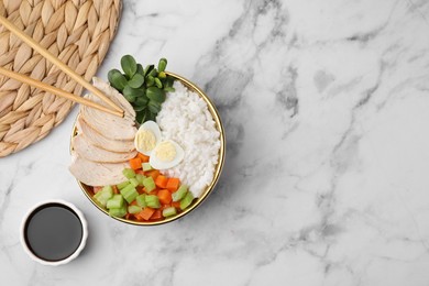 Delicious poke bowl of meat, egg, rice and vegetables served with soy sauce on white marble table, flat lay. Space for text