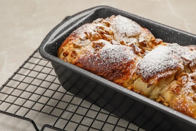 Photo of Delicious yeast dough cake in baking pan on beige table, closeup