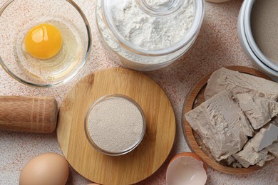 Photo of Different types of yeast, flour and eggs on orange textured table, flat lay