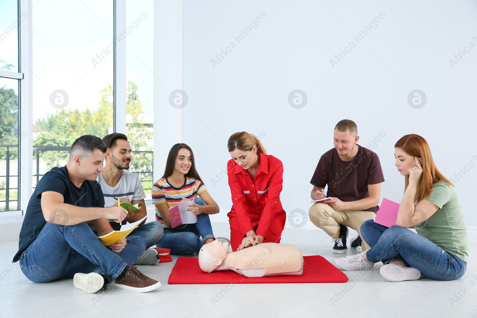 Photo of Instructor demonstrating CPR on mannequin at first aid class indoors