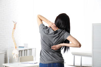 Photo of Woman suffering from pain in back at clinic. Visiting orthopedist