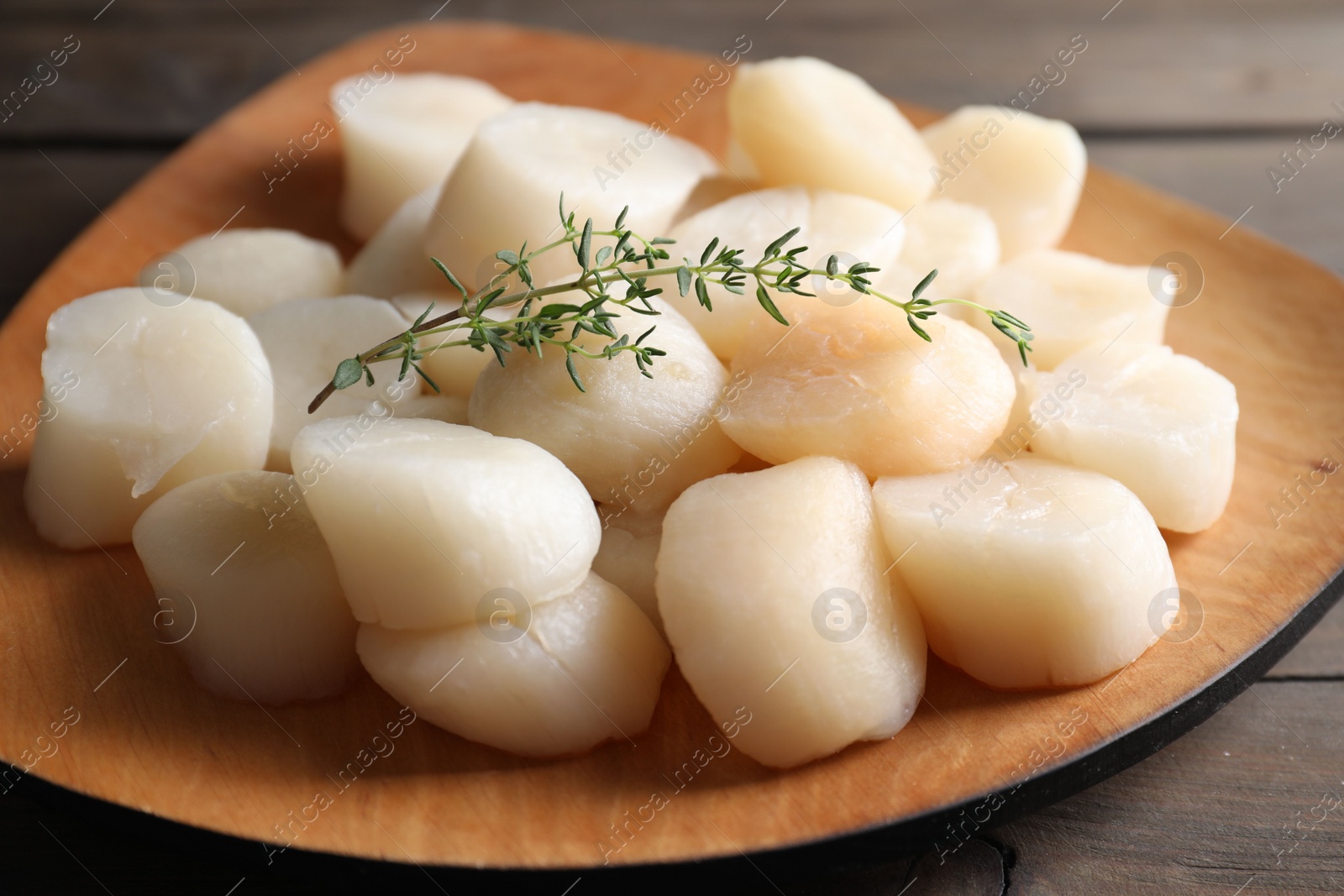 Photo of Fresh raw scallops and thyme on wooden table, closeup