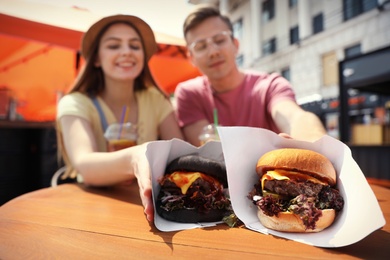 Young happy couple with burgers in street cafe, closeup