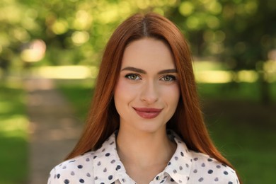 Photo of Portrait of beautiful young woman with red hair outdoors. Attractive lady looking into camera