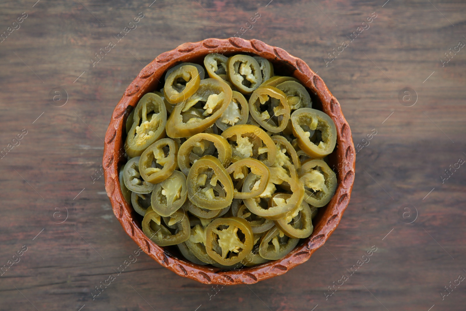 Photo of Pickled green jalapeno peppers on wooden table, top view