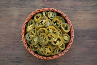 Photo of Pickled green jalapeno peppers on wooden table, top view