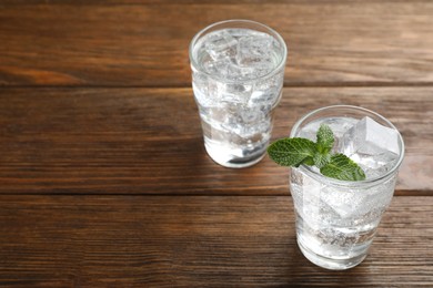 Photo of Glasses of soda water with ice and mint on wooden table. Space for text