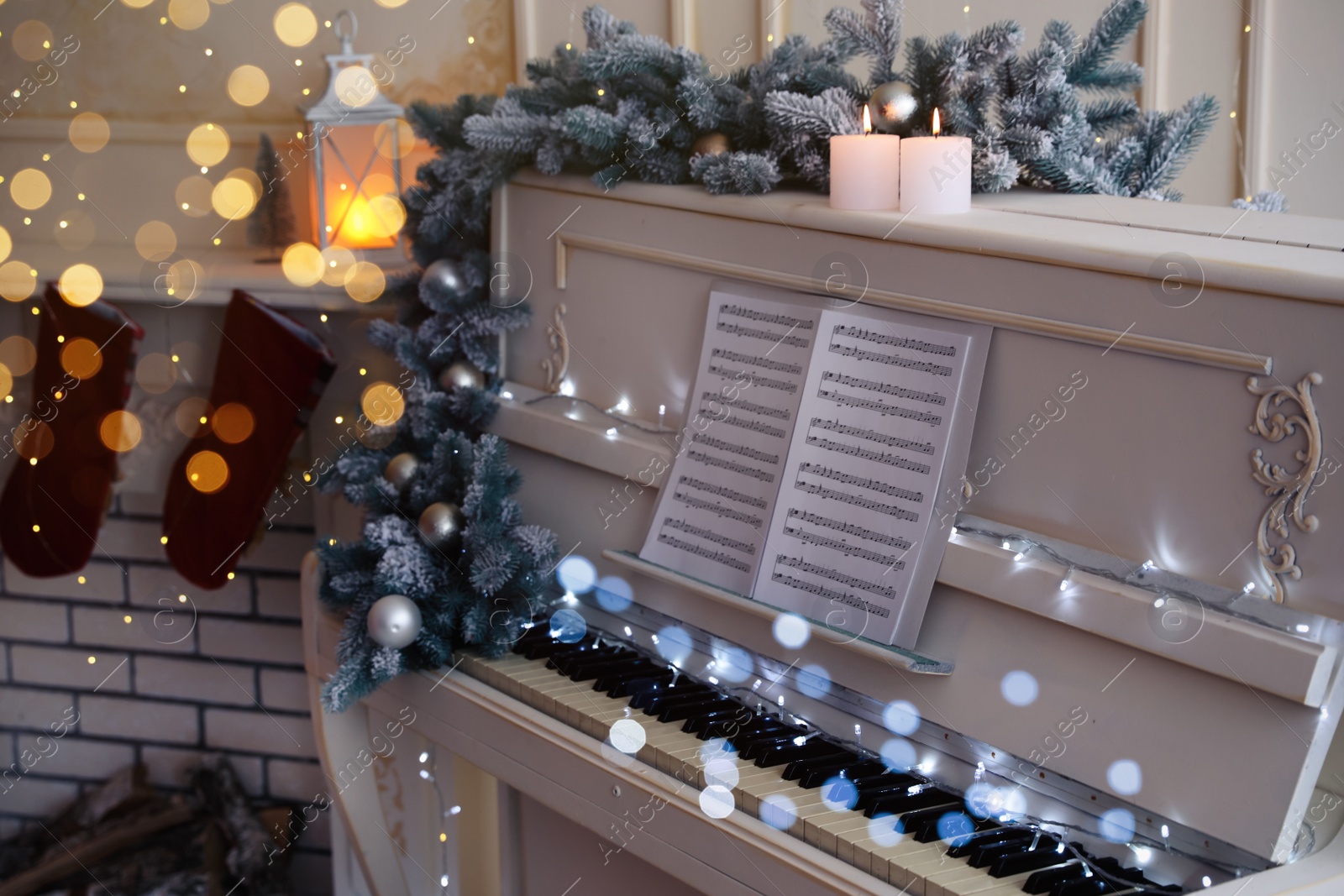 Photo of White piano with festive decor and note sheets indoors. Christmas music