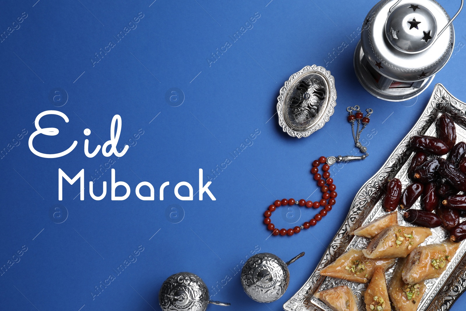 Image of Eid Mubarak greeting card. Flat lay composition with Arabic lantern and misbaha on blue background