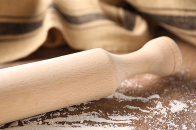 Photo of Rolling pin and scattered flour on wooden table, closeup