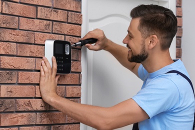 Male technician installing alarm system indoors