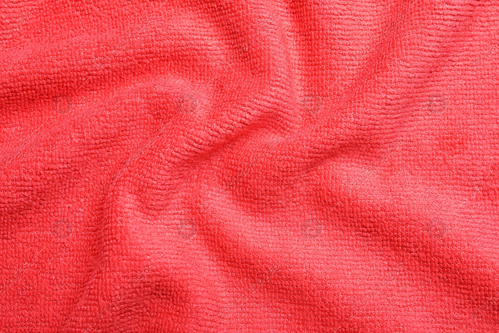 Photo of Crumpled red microfiber cloth as background, closeup