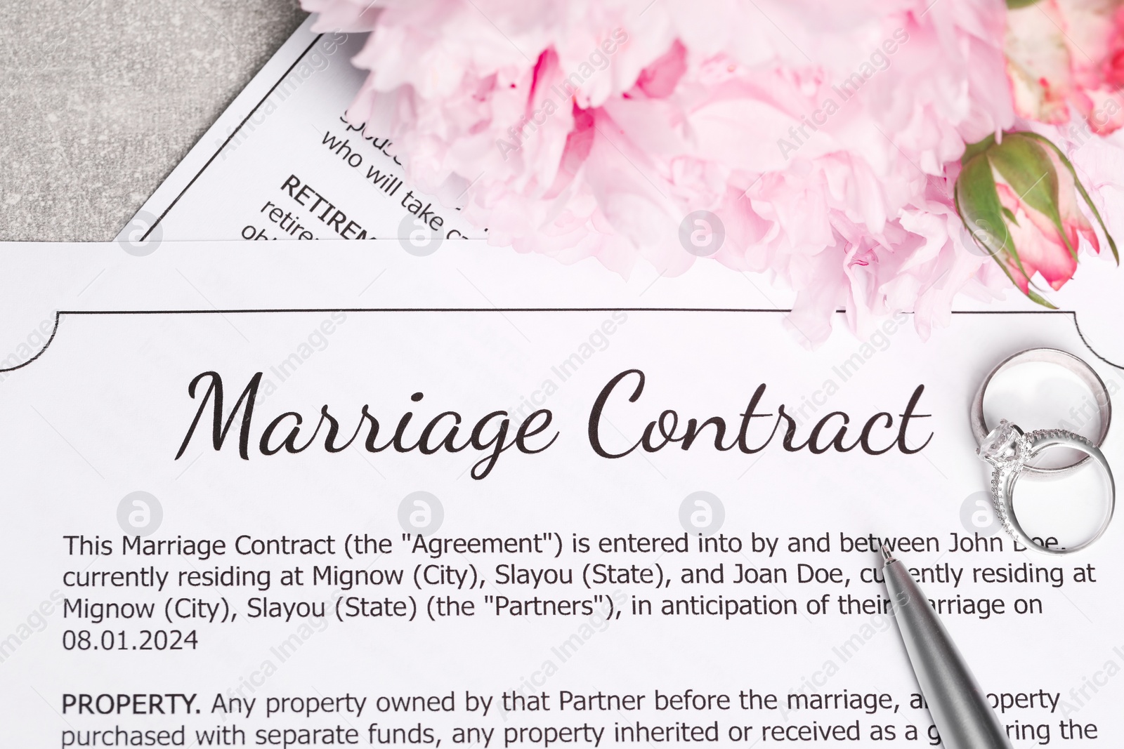 Photo of Marriage contract, wedding rings, pen and flowers on grey table, top view