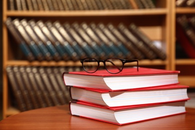 Stack of books and glasses on table in library. Space for text