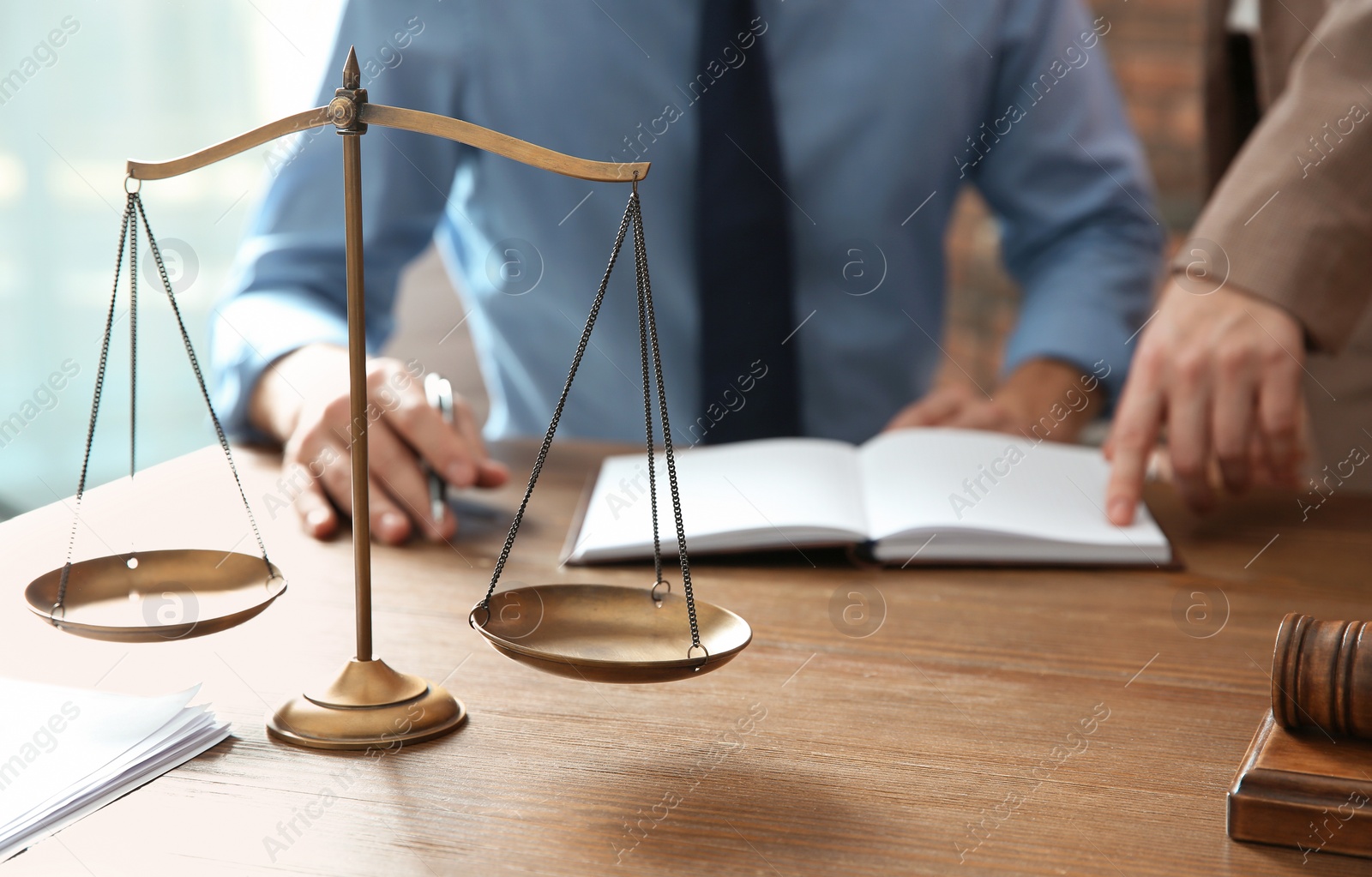 Photo of Notaries working at table in office, focus on scales of justice. Law concept