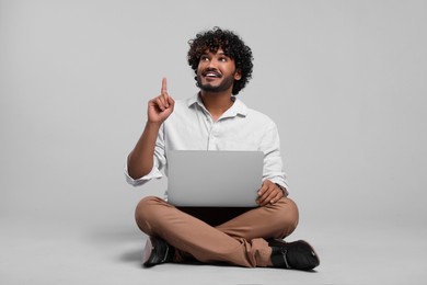 Photo of Smiling man with laptop on light grey background, space for text