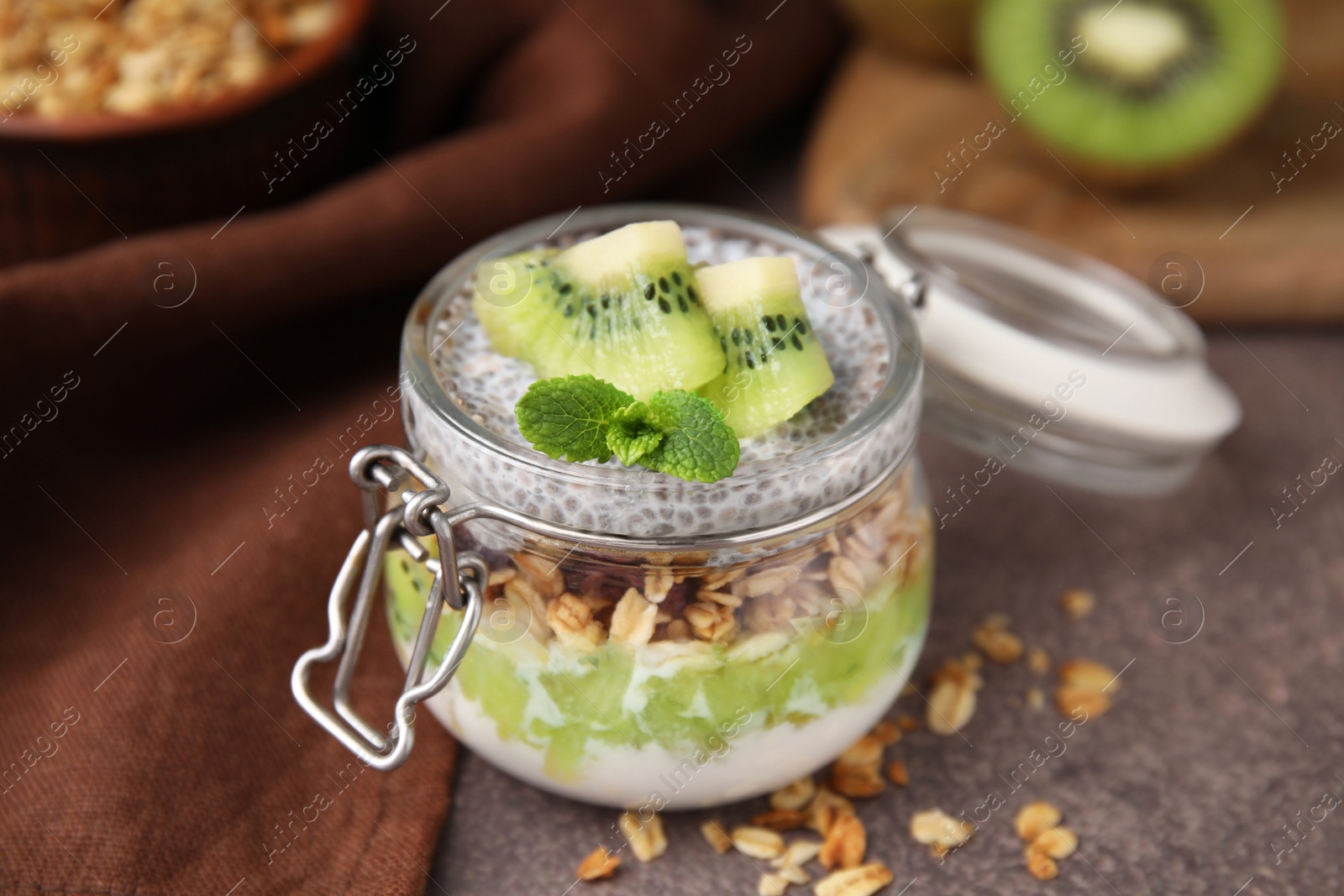 Photo of Delicious dessert with kiwi and chia seeds on brown table, closeup