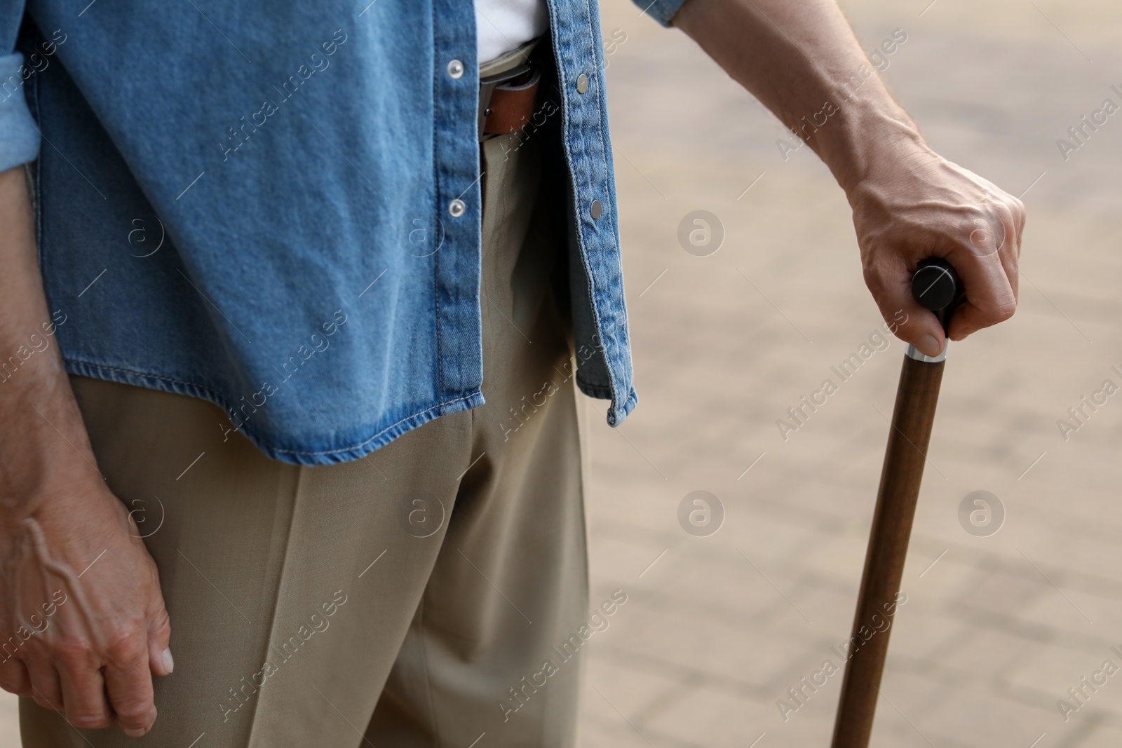 Photo of Senior man with walking cane outdoors, closeup