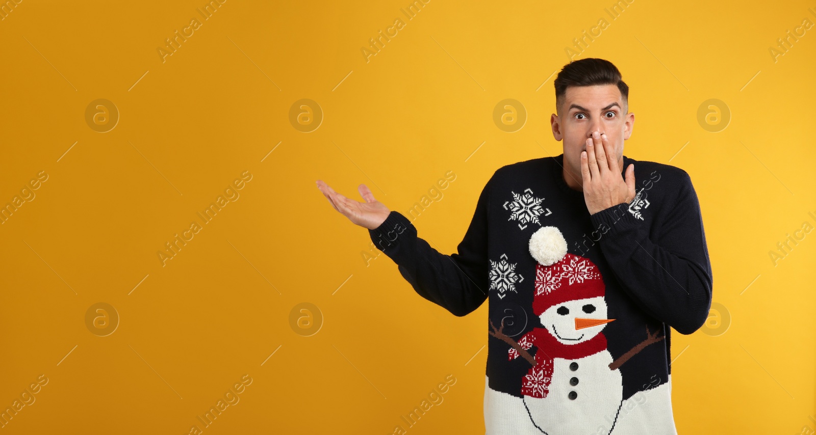 Photo of Shocked man in Christmas sweater on yellow background