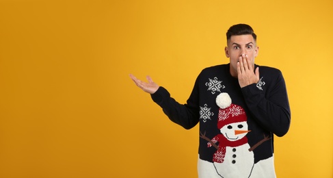 Photo of Shocked man in Christmas sweater on yellow background