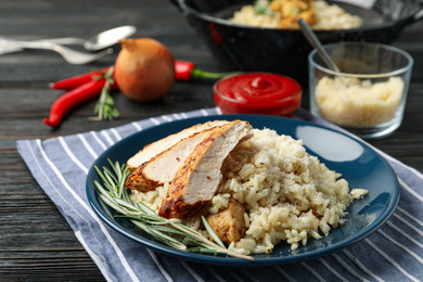 Photo of Delicious risotto with chicken served on wooden table