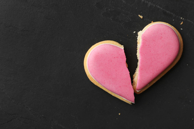 Photo of Broken heart shaped cookie on black table, top view with space for text. Relationship problems concept