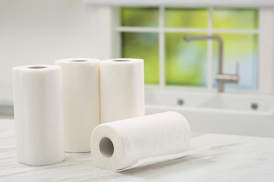 Photo of Many rolls of paper towels on white marble table in kitchen