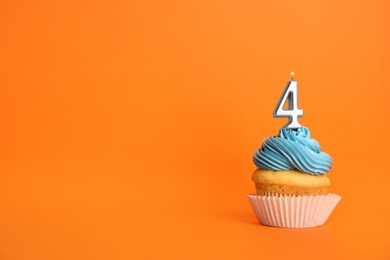 Birthday cupcake with number four candle on orange background, space for text