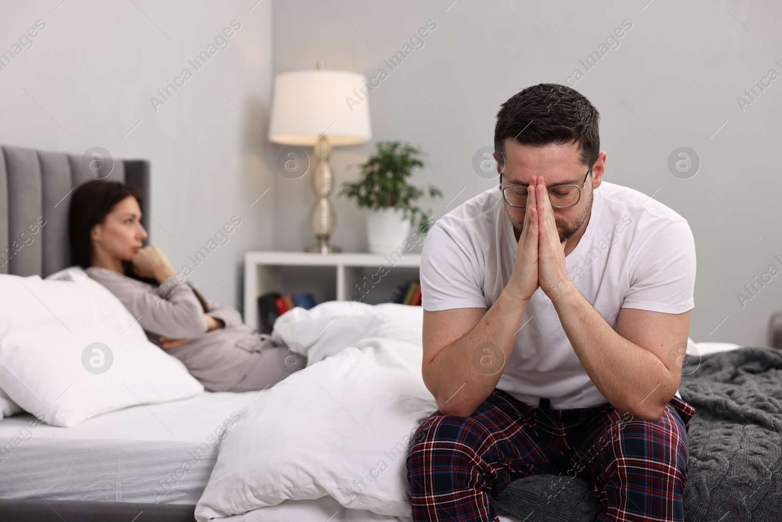 Photo of Offended couple ignoring each other after quarrel in bedroom, selective focus. Relationship problems