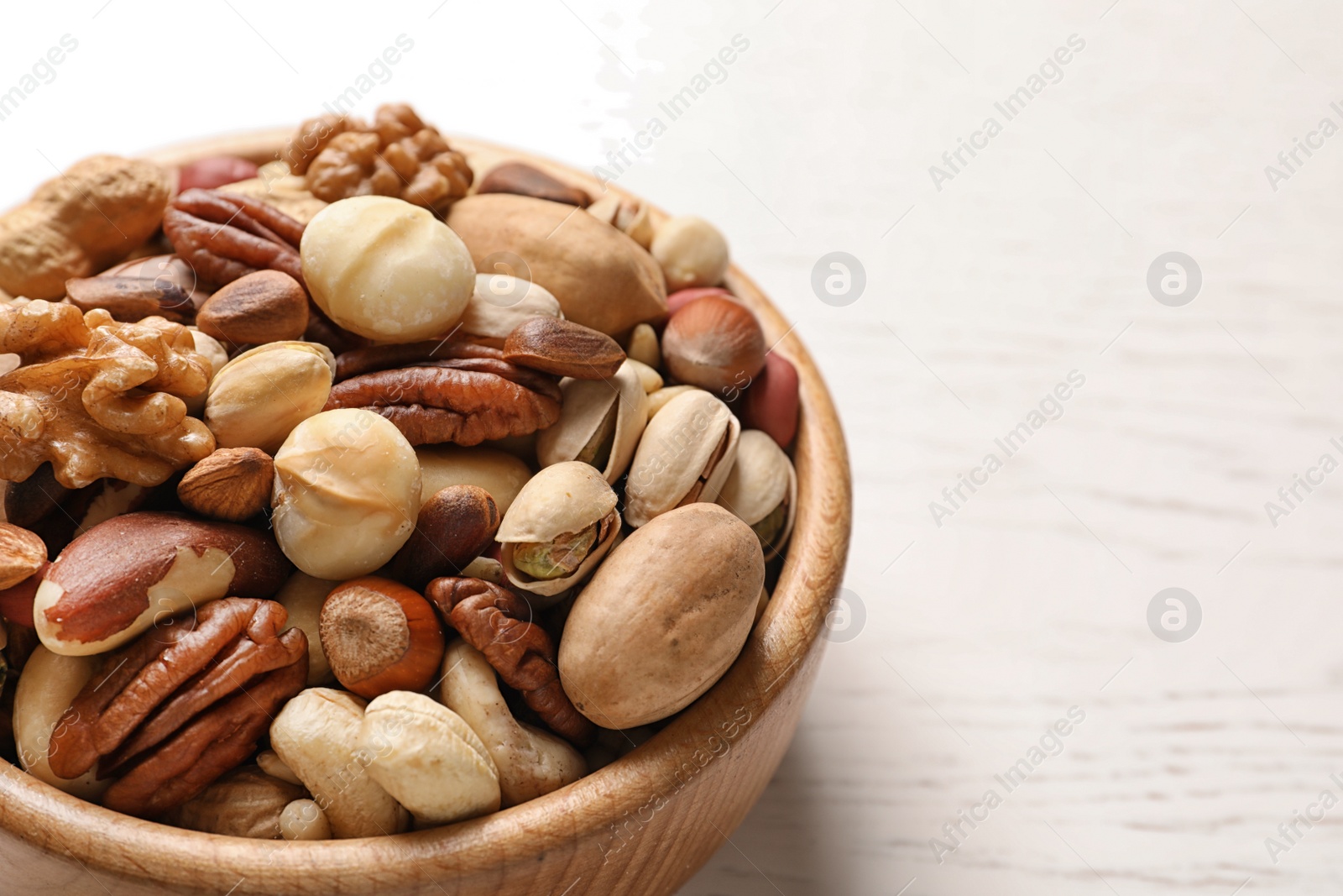 Photo of Bowl with organic mixed nuts on table, closeup. Space for text