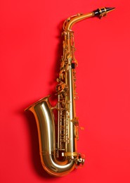 Photo of Beautiful saxophone on red background, top view