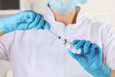 Nurse filling syringe with monkeypox vaccine from glass vial in hospital, closeup