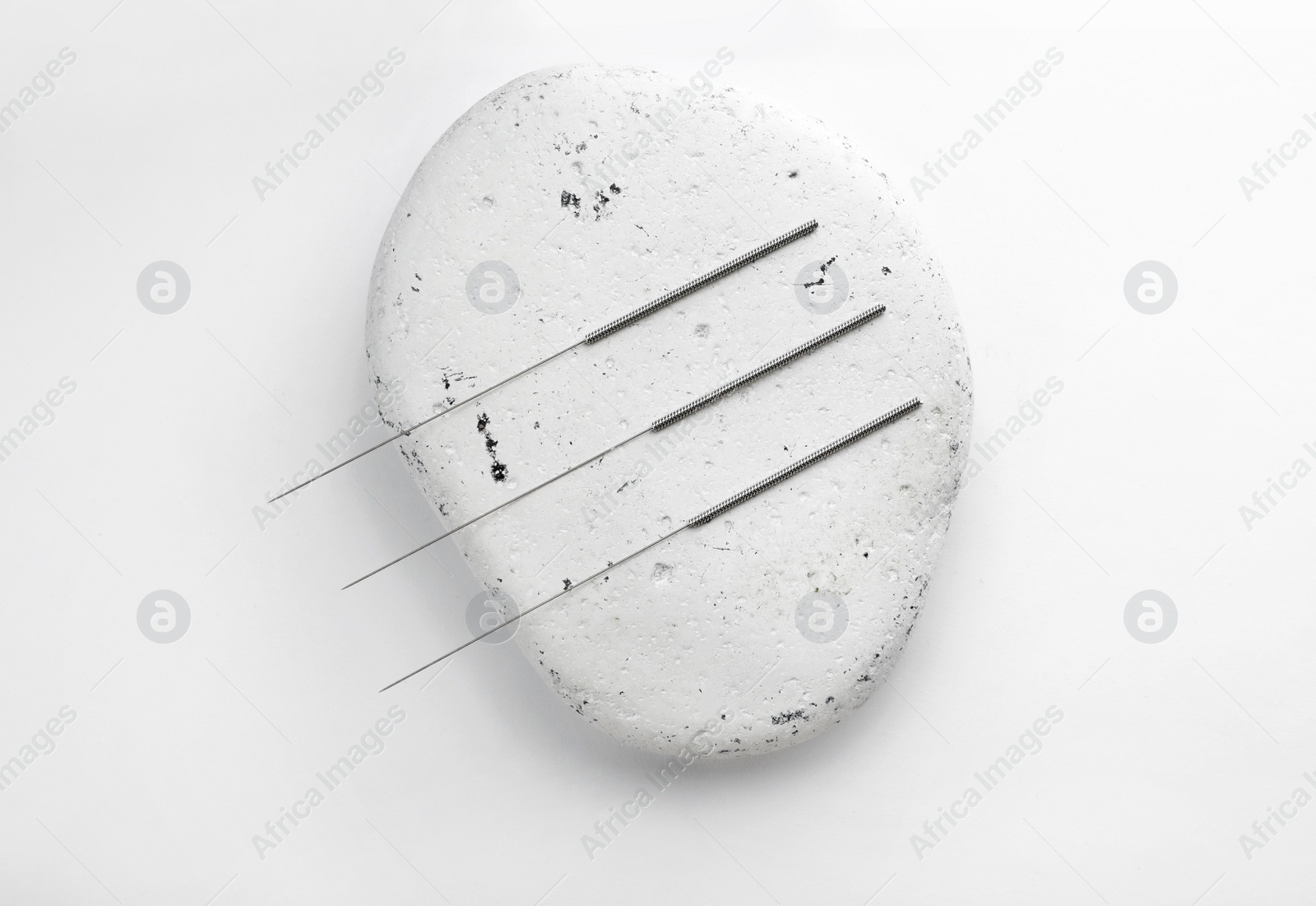 Photo of Needles for acupuncture and stone on white background