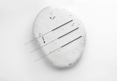 Needles for acupuncture and stone on white background