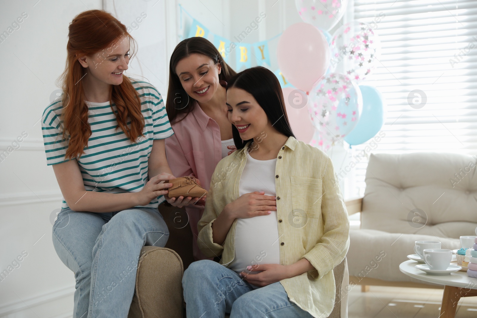 Photo of Happy pregnant woman spending time with friends at baby shower party