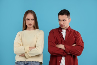 Photo of Portrait of resentful couple with crossed arms on light blue background