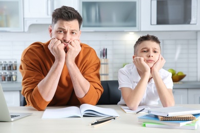 Photo of Dad helping his son with difficult homework assignment in kitchen